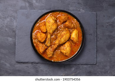 Chicken curry or masala,Kerala style chicken curry using fried coconut in traditional way and arranged in a black  ceramic vessel which is placed on a graphite sheet with grey background,isolated. - Shutterstock ID 1903754356