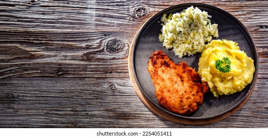 Chicken cutlet coated with breadcrumbs served with potatoes and cabbage - Shutterstock ID 2254051411
