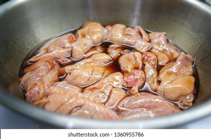 Chicken Drum Sticks And Wings Marinated In A Metal Mixing Bowl