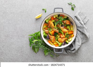 Chicken Drumsticks Roasted With Vegetables In Cast Iron Pan On Kitchen Table, Top Down View