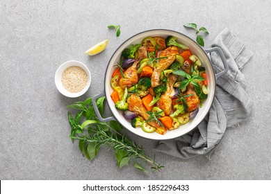 Chicken Drumsticks Roasted With Vegetables In Cast Iron Pan On Kitchen Table, Top Down View