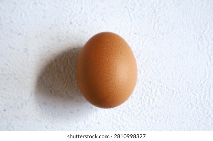A chicken egg is positioned upright and placed against a white background.