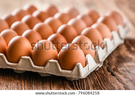 Chicken eggs in carton box on wooden table. 