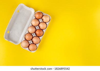 Chicken Eggs In An Open Egg Carton Isolated On Yellow. Top View With Copy Space. Natural Healthy Food And Organic Farming Concept. 