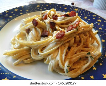 
	Chicken fettuccini alfredo on a white plate with a blue border			