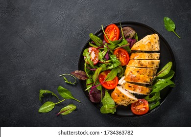 Chicken fillet with salad from leaves and vegetables. Healthy food, keto diet, diet lunch concept. Top view on black background with copy space. - Powered by Shutterstock