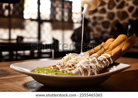 Chicken flautas with cheese and cream accompanied by guacamole in a typical Mexican food restaurant