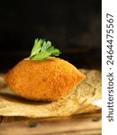 Chicken Kiev on backing paper with parsley on black background