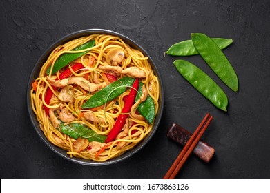 Chicken Lo Mein In Black Bowl At Dark Slate Background. Lo Mein Is Chinese Cuisine Dish With Chicken Meat, Egg Noodles, Vegetables And Sauces. Chinese Food. Stir Fried Noodles. Top View