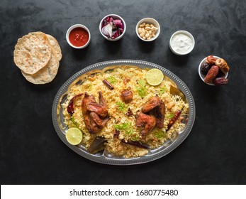 Chicken Mandi with dates on a black table. Arabic cuisine. Top view.