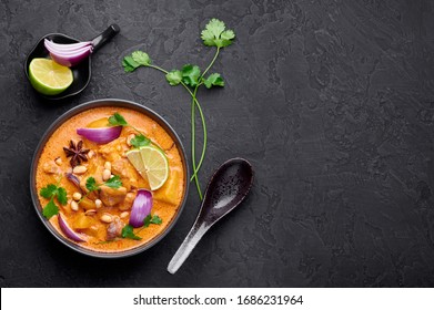 A Chicken Massaman Curry In Black Bowl At Dark Slate Background. Massaman Curry Is Thai Cuisine Dish With Chicken Meat, Potato, Onion And Many Spices. Thai Food. Copy Space. Top View