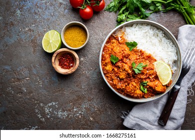 Chicken meat with tikka masala sauce, spicy curry food in a bowl with rice and seasonings, top view