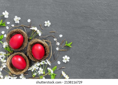 Chicken nests with painted Easter eggs on dark tabletop. Holiday greeting card. Concept creative banner Flat lay  top view with copy space.