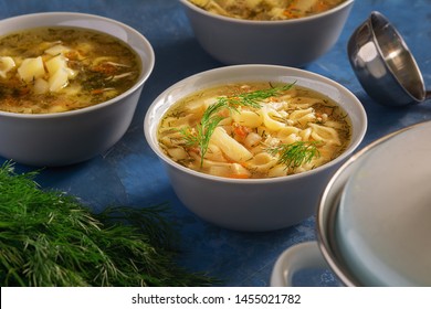 Chicken Noodle Soup With Vegetables Home Recipe. Homemade Healthy First Course Served In White Bowl. Poultry Broth With Traditional Pasta Elevated View. Nutritious Dinner. Tureen And Ladle On Table