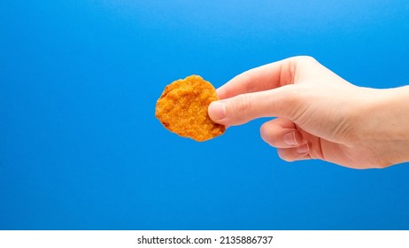 Chicken Nugget In Hand On A Blue Background