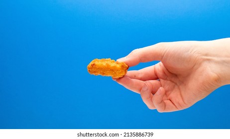 Chicken Nugget On Side In Hand On A Blue Background