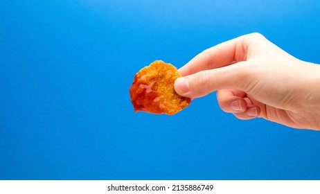 Chicken Nugget With Sauce In Hand On A Blue Background