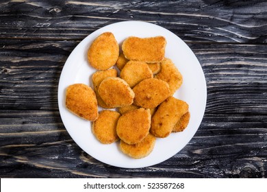 Chicken nuggets on a white plate on a rustic background