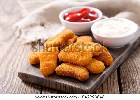 chicken nuggets with sauces on wooden board
