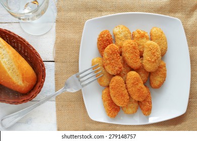 chicken nuggets served in a white bowl on a white wooden table of a rustic kitchen