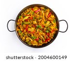 Chicken paella on white background, a traditional Valencian (Spanish) dish made of rice with chicken and vegetables in a pan. view from above, flat lay