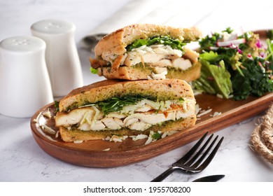 Chicken Panini has Chicken - pesto - mozzarella - rocket - olive panini bread in brown wooden plate, on white background 