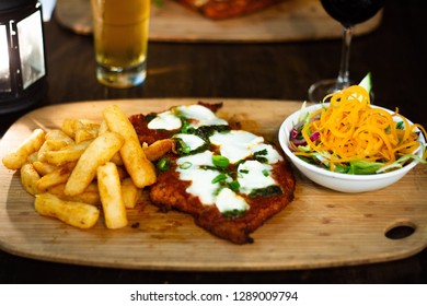 Chicken Parma With Chips And Salad On A Wooden Plate With Beer And Wine 