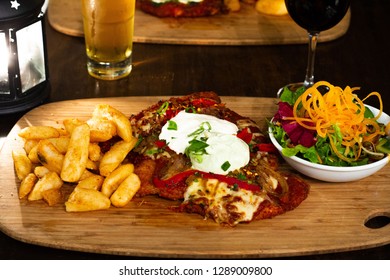 Chicken Parma With Chips And Salad On A Wooden Plate With Beer And Wine 