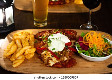 Chicken Parma With Chips And Salad On A Wooden Plate With Beer And Wine 