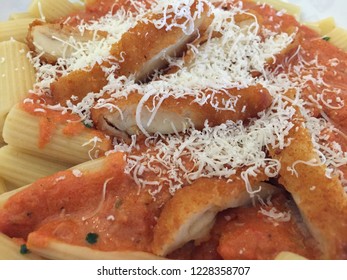 Chicken Parmesan Deconstructed: Breaded And Fried Chicken Cutlet Sliced And Served Over Rigatoni Pasta With Marinara Sauce And Grated Parmesan Cheese On White Plate