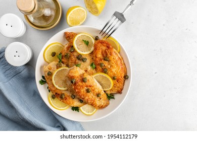 Chicken Piccata On White Table Directly Above. Chicken Breast Dredged In Flour And Cooked In Sauce Cantaining Lemon Juice, Butter And Capers. 