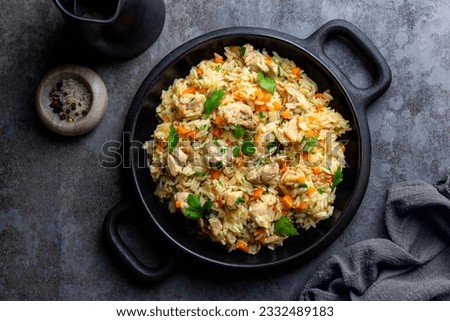 Chicken Pilaf, pilau or biryani. Dish made of long-grain rice, onion, carrots, spices and parsley. Eastern cuisine. Dark background, top view.