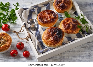 Chicken Pot Pie With Creamy Filling Of Cream, Carrot, Celery, Peas, Chicken Breast, With Puff Pastry Crust On Top, Served In The Individual Ramekin, On A White Wooden Table, Close Up