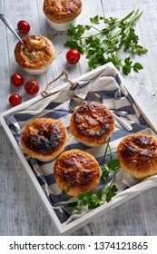 Chicken Pot Pie With Creamy Filling Of Cream, Carrot, Celery, Peas, Chicken Breast, With Puff Pastry On Top, In The Individual Ramekin, On A White Wooden Table, Close Up, Vertical View From Above