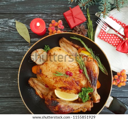 chicken roast whole christmas on a wooden background, fork, knife, plate, bow
