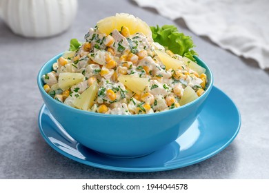 Chicken salad with pineapple and corn served in a blue bowl on a light background.