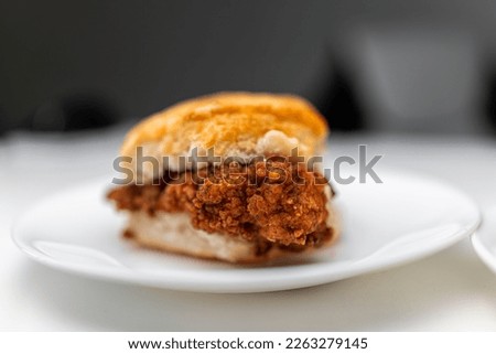 Chicken sandwich deep fried crispy meat on breakfast biscuit buns bread, fresh fast food on one white background kitchen table plate macro closeup