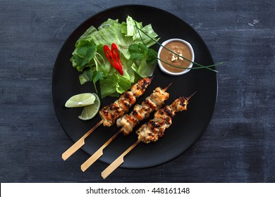 Chicken Satay or Sate Ayam - Malaysian famous food. Satay, modern Indonesian and Malay spelling of sate, is a dish of seasoned, skewered and grilled meat, served with a peanut sauce. Top view