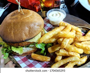 Chicken Schnitzel Burger Bun Served With Fries Or Potato Chips And Aioli Sauce.