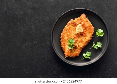 Chicken schnitzel on plate over dark background  with copy space. Top view, flat lay