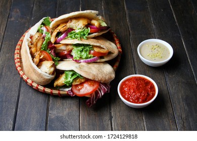 Chicken Shawarma In Pita Aish With Sauces Harissa And Tahini On Black Wooden Background. Top View, Flat Lay. Ramadan Food Concept.