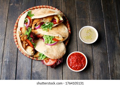 Chicken Shawarma In Pita Aish With Sauces Harissa And Tahini On Black Wooden Background. Top View, Flat Lay. Ramadan Food Concept.