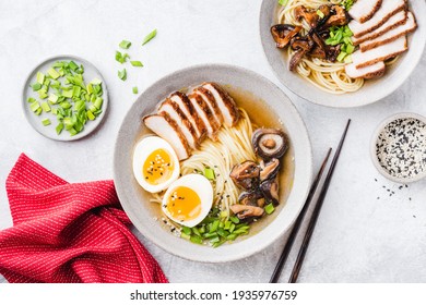Chicken shiitake ramen noodle soup bowl on a grey concrete background, top view. Asian cuisine food, noodle soup with chicken, shiitake, egg and green onion known as Ramen