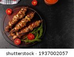 Chicken skewers with apples and vegetables on a black background