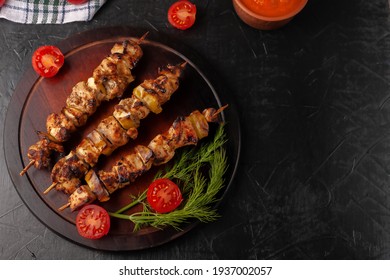 Chicken skewers with apples and vegetables on a black background
