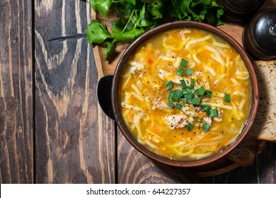 chicken soup with egg noodles on wooden background, top view, horizontal