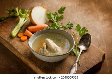 chicken soup witn ingredients over cutting board