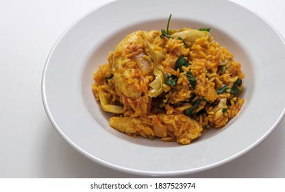 Chicken With Spanish Rice And Artichoke Hearts Served In A White Round Shallow Gourmet Bowl