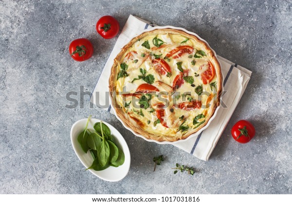 Chicken, spinach and tomatoes pie( quiche) on a blue\
stone background. Top\
view