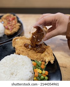Chicken Steak With BBQ Sauce. Close Up And With Hand Pouring The Sauce. Fusion With Indonesian Culture. Using Rice Instead With Potato